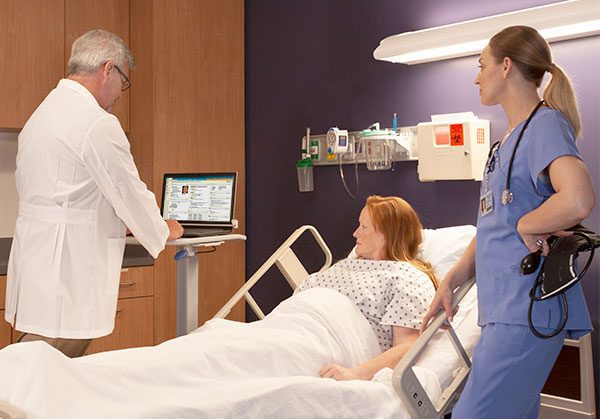 Nurse using SlimCart Laptop Documentation Cart at patient bedside